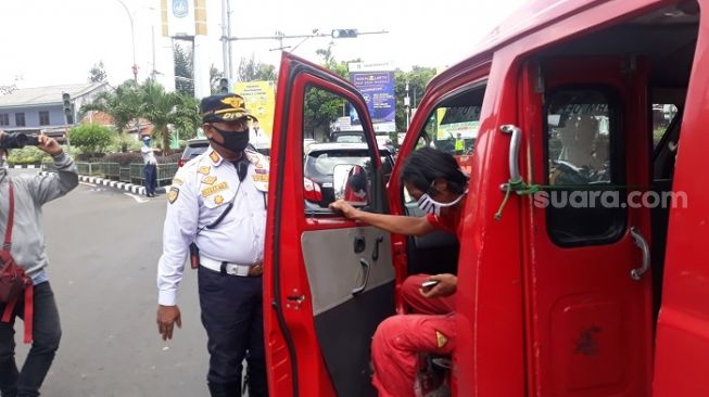 Petugas Dishub saat mengatur angkutan umum terkait pemberlakuan PSBB di Kota Depok. (Suara.com/Novian).