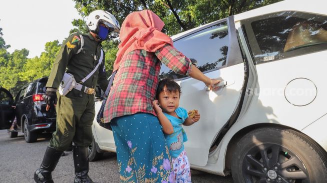 Penumpang mobil pindah ke bagian belakang untuk mentaati aturan PSBB saat dihentikan petugas di Check Point PSBB Kota Depok dibawah Flyover UI, Lenteng Agung, Jakarta Selatan, Rabu (15/4). [Suara.com/Alfian Winanto]