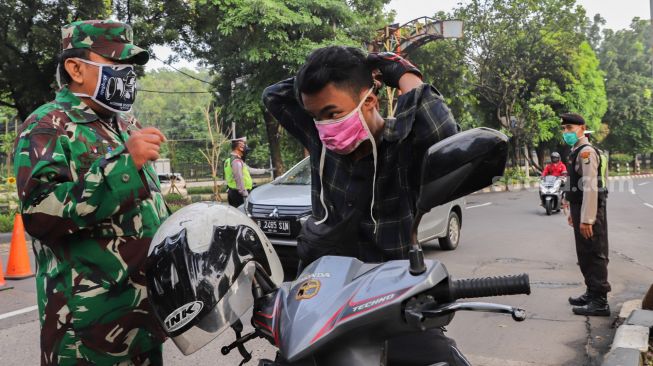 Pengendara memakai masker saat dihentikan oleh petugas di Check Point PSBB Kota Depok dibawah Flyover UI, Lenteng Agung, Jakarta Selatan, Rabu (15/4). [Suara.com/Alfian Winanto]