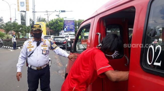 Petugas Dishub saat mengatur angkutan umum terkait pemberlakuan PSBB di Kota Depok. (Suara.com/Novian).