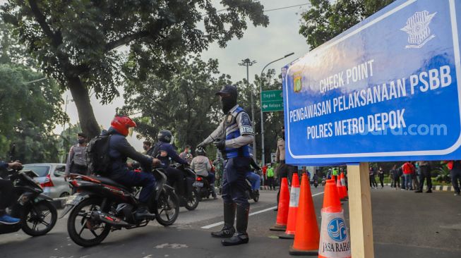 Petugas berjaga di Check Point PSBB Kota Depok yang ada dibawah Flyover UI, Lenteng Agung, Jakarta Selatan, Rabu (15/4). [Suara.com/Alfian Winanto]