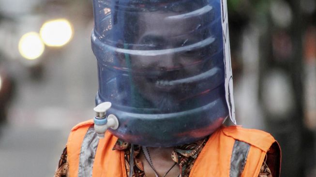 Ali Akbar Sukarelawan Pengatur Lalu Lintas (Supeltas) mengatur lalu lintas mengenakan pelindung wajah dari galon bekas di Jalan Tamansiswa, DI Yogyakarta, Rabu (15/4).   [ANTARA FOTO/Hendra Nurdiyansyah]