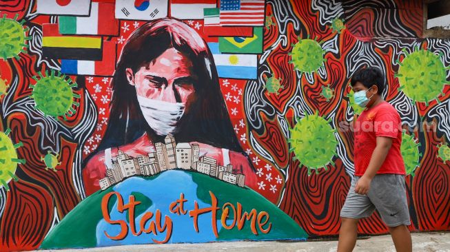 Seorang anak melintas didepan mural "Stay At Home" bertemakan virus Corona di Cipayung, Depok, Jawa Barat, Rabu (15/4). [Suara.com/Alfian Winanto]