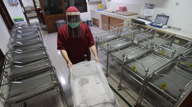 Perawat mengantarkan bayi yang memakai pelindung muka atau face shield di RS Ibu dan Anak Asih, Jakarta, Jumat (17/4). [ ANTARA FOTO/Puspa Perwitasari]