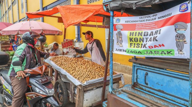 Himbauan untuk Physical Distancing bagi pedagang di Pasar Minggu, Jakarta Selatan, Jumat (17/4). [Suara.com/Alfian Winanto]
