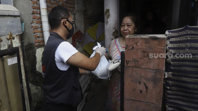 Pengurus membagikan beras kepada warga di kawasan Petamburan, Jakarta, Jumat (17/4). [Suara.com/Angga Budhiyanto]