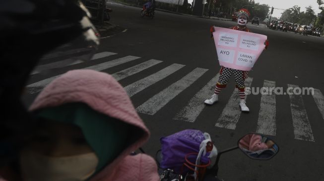 Badut yang tergabung dalam Aku Badut Indonesia (ABI) melakukan kampanye melawan virus Corona di kawasan Pasar Rebo, Jakarta, Sabtu (18/4). [Suara.com/Angga Budhiyanto]