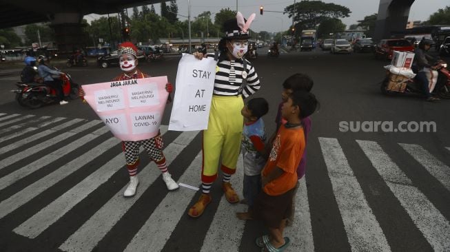 Badut yang tergabung dalam Aku Badut Indonesia (ABI) melakukan kampanye melawan virus Corona di kawasan Pasar Rebo, Jakarta, Sabtu (18/4). [Suara.com/Angga Budhiyanto]