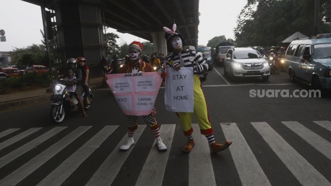 Badut yang tergabung dalam Aku Badut Indonesia (ABI) melakukan kampanye melawan virus Corona di kawasan Pasar Rebo, Jakarta, Sabtu (18/4). [Suara.com/Angga Budhiyanto]