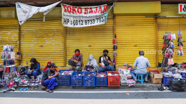 Deretan pedagang masker didepan pertokoan yang tutup di Pasar Asemka, Jakarta Barat, Minggu (19/4). [Suara.com/Alfian Winanto]
