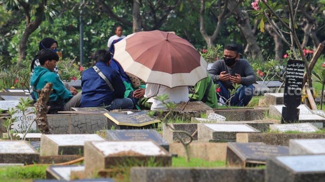 Warga berdoa di makam kerabatnya di Tempat Pemakaman Umum (TPU) Karet Bivak, Jakarta Pusat, Minggu (19/4). [Suara.com/Alfian Winanto]