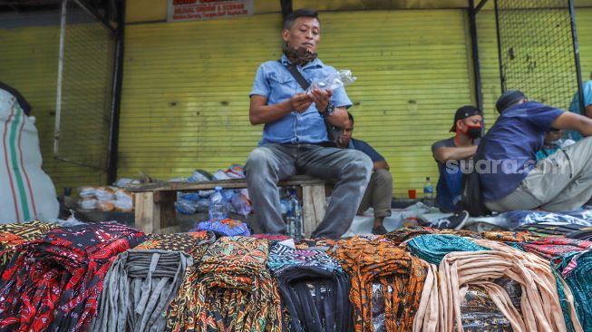 Pedagang menjajakan masker jualannya di Pasar Asemka, Jakarta Barat, Minggu (19/4). [Suara.com/Alfian Winanto]