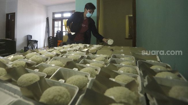 Relawan menata makanan di kafe milik sekelompok pemuda yang diubah menjadi dapur umum yang dinamai 'Dapur Untuk Rakyat' di kawasan Pisangan, Ciputat, Tangerang Selatan, Senin (20/4). [Suara.com/Angga Budhiyanto]