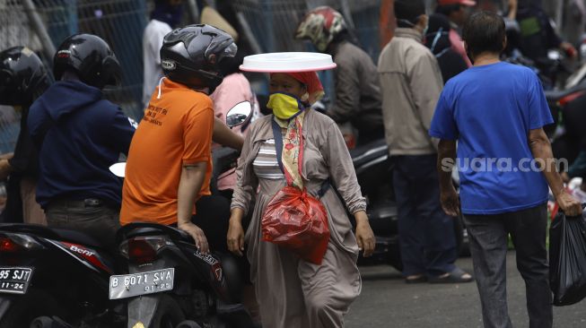 Pedagang membawa barang dagangannya melintas di kawasan Pasar Minggu, Jakarta, Selasa (21/4). [Suara.com/Angga Budhiyanto]











