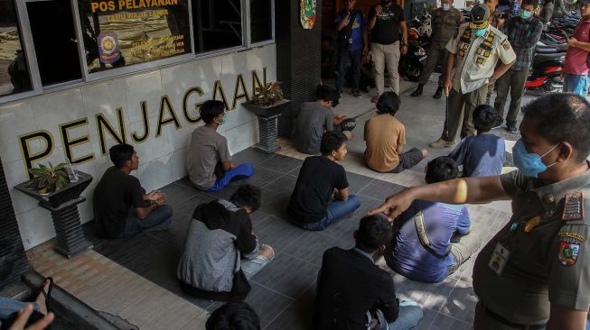 Petugas Satpol PP Kota Pekanbaru mendata remaja yang kedapatan bermain di warung internet (warnet) saat penerapan Pembatasan Sosial Berskala Besar (PSBB) di Kota Pekanbaru, Riau, Senin (20/4).  [ANTARA FOTO/Rony Muharrman]