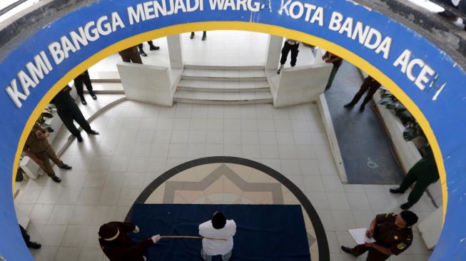 Terpidana (tengah) pelanggar hukum syariat Islam dieksekusi cambuk di Banda Aceh, Aceh, Selasa (21/4). [ANTARA FOTO/Irwansyah Putra]