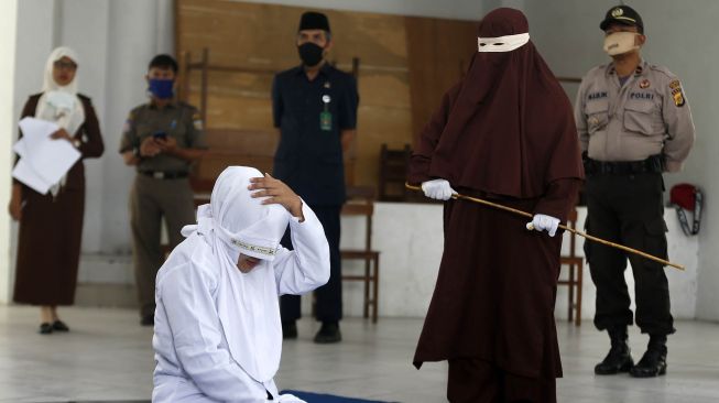 Terpidana (duduk) pelanggar hukum syariat Islam dieksekusi cambuk di Banda Aceh, Aceh, Selasa (21/4).   [ANTARA FOTO/Irwansyah Putra]
