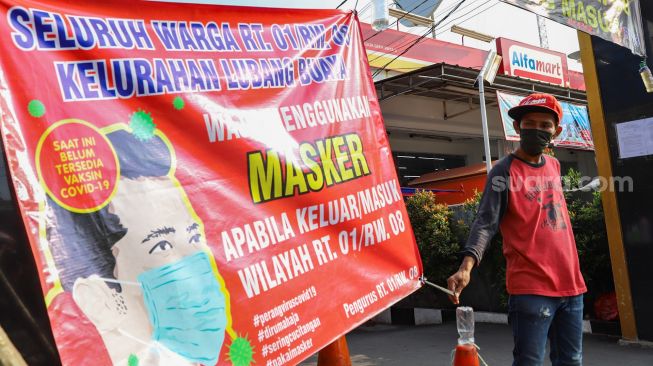 Warga berjaga didepan gerbang karantina wilayah Di Jalan Kramat Pangeran Syarif, Lubang Buaya, Jakarta Timur (22/4). [Suara.com/Alfian Winanto]