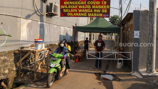 Warga Gang Langgar RW 08 melakukan karantina wilayah atau Lockdown Mandiri di Jalan Monumen Pancasila Sakti, Lubang Buaya, Jakarta Timur (22/4). [Suara.com/Alfian Winanto]
