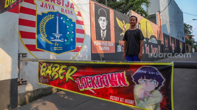 Warga berjaga di depan Gang Gaber RT 13/02 di Jalan Raya Pondok Gede, Lubang Buaya, Jakarta Timur (22/4). [Suara.com/Alfian Winanto]