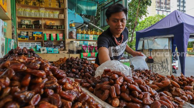 Pedagang merapikan kurma yang akan dijual ke pembeli di Pasar Tanah Abang, Jakarta Pusat, Kamis (23/4). [Suara.com/Alfian Winanto]