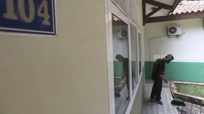 Petugas Badan Layanan Umum Daerah (BLUD) menyapu salah satu kamar yang akan dijadikan tempat tinggal sementara tenaga medis penanganan Corona (Covid-19) di SMK Negeri 57, Jakarta, Kamis (23/4). [Suara.com/Angga Budhiyanto]