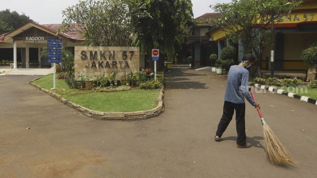 Petugas Badan Layanan Umum Daerah (BLUD) menyapu  di SMK Negeri 57, Jakarta, Kamis (23/4). [Suara.com/Angga Budhiyanto]