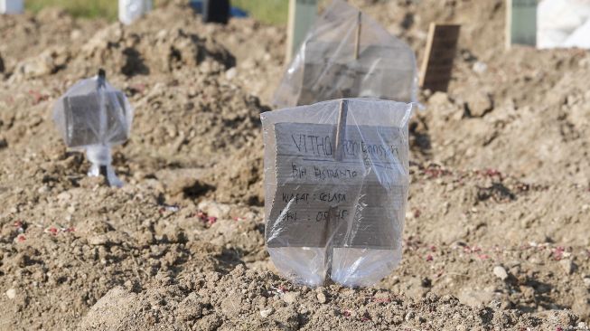 Tanda pengenal yang terbuat dari kardus berada di makam  kasus meninggal akibat virus Corona COVID-19 sebagai pengganti nisan di komplek TPU Tegal Alur, Jakarta, Rabu (22/4).  [ANTARA FOTO/Muhammad Adimaja]