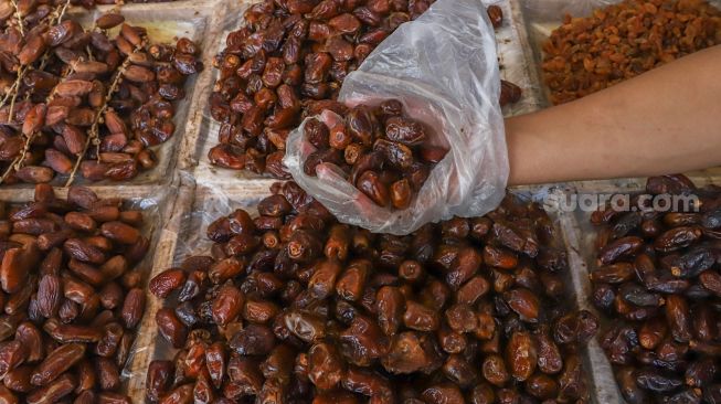 Pembeli memilih jenis kurma di Pasar Tanah Abang, Jakarta Pusat, Kamis (23/4). [Suara.com/Alfian Winanto]
