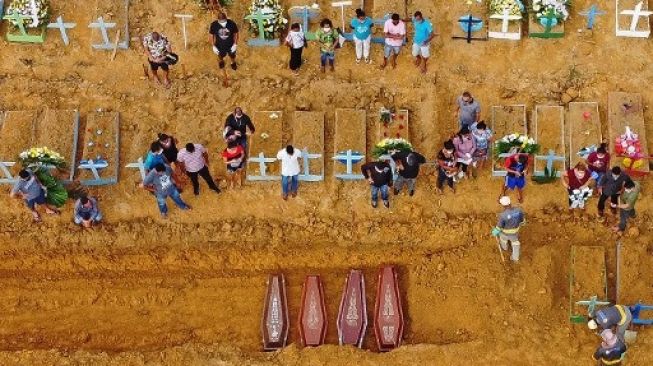 Mobil alat berat menggali kubur bagi korban meninggal akibat virus corona di kota Manaus, Brasil, yang mencapai 100 kematian per hari. [AFP]