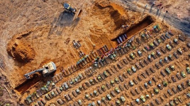 Mobil alat berat menggali kubur bagi korban meninggal akibat virus corona di kota Manaus, Brasil, yang mencapai 100 kematian per hari. [AFP]