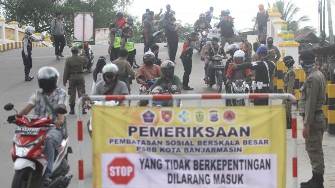 Petugas memeriksa identitas diri warga saat hari pertama Pembatasan Sosial Berskala Besar (PSBB) di perbatasan Kota Banjarmasin, Kalimantan Selatan, Jumat (24/4). [ANTARA FOTO/Bayu Pratama]