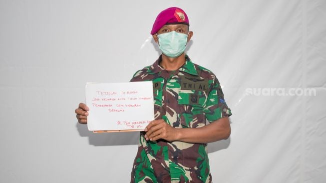 Seorang Anggota TNI berpose sambil memperlihatkan pesannya saat difoto di Markas Pusat PMI, Mampang, Jakarta Selatan, Rabu (25/3). [Suara.com/Alfian Winanto]