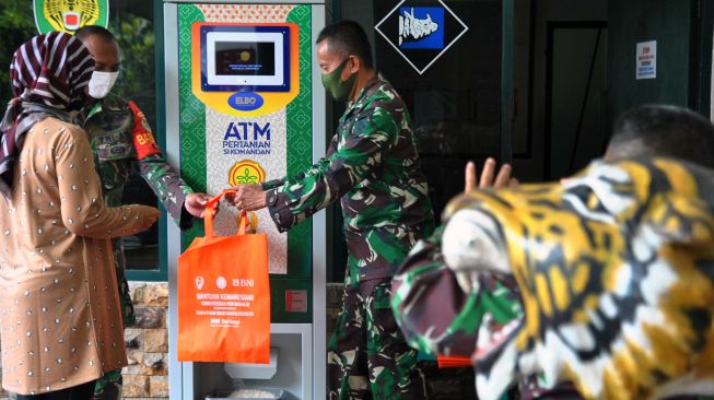 Anggota Kodim 0606/Kota Bogor membantu warga mendapatkan beras dengan menggunakan ATM Pertanian Sikomandan di Kodim 0606/Kota Bogor, Jawa Barat, Sabtu (25/4). [ANTARA FOTO/Arif Firmansyah]