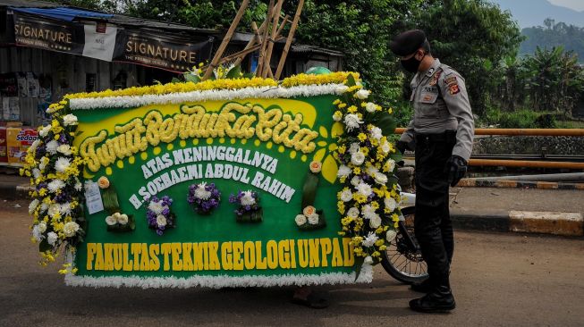 Petugas memberhentikan kendaraan bermotor yang membawa karangan bunga duka cita, di titik penyekatan larangan mudik di Jatinangor, perbatasan Kabupaten Bandung dan Kabupaten Sumedang, Jawa Barat, Sabtu (25/4).  [ANTARA FOTO/Raisan Al Farisi]