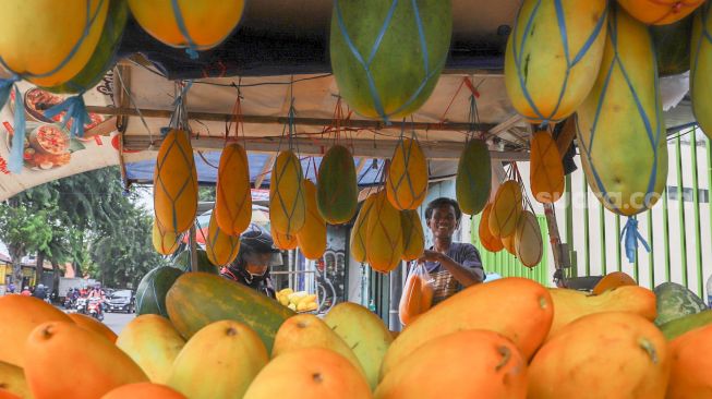 Pembeli membayar buah Timun Suri yang dibelinya untuk berbuka puasa di Pasar Palmerah, Jakarta Pusat, Sabtu (25/4). [Suara.com/Alfian Winanto]
