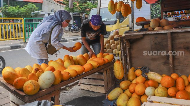 Pembeli memilih buah Timun Suri di Pasar Palmerah, Jakarta Pusat, Sabtu (25/4). [Suara.com/Alfian Winanto]