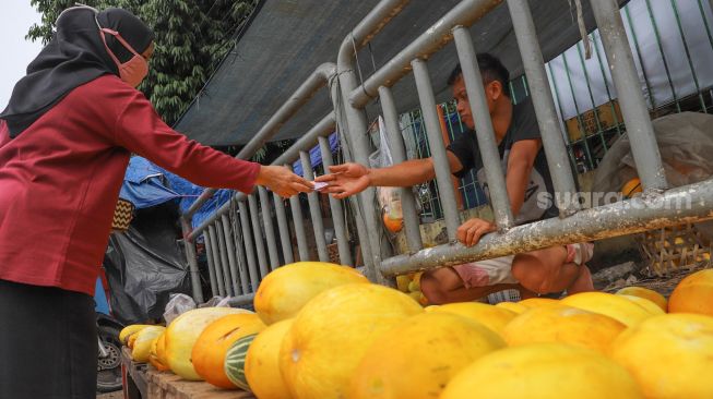 Pembeli membayar buah Timun Suri yang dibelinya di Pasar Palmerah, Jakarta Pusat, Sabtu (25/4). [Suara.com/Alfian Winanto]
