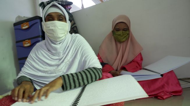 Penyandang disabilitas tunanetra membaca kitab suci Al Quran yang menggunakan cetakan huruf braille di Persatuan Tuna Netra Indonesia (Pertuni) Sumut Medan, Sumatera Utara, Minggu (26/4). [ANTARA FOTO/Septianda Perdana]