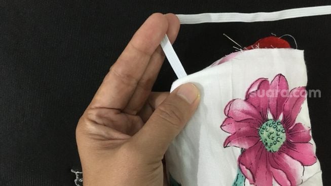 Cara jahit ban elastik di masker kain yang sudah jadi. Bisa stich bali, feston, atau jelujur biasa [Suara.com/CNR ukirsari].