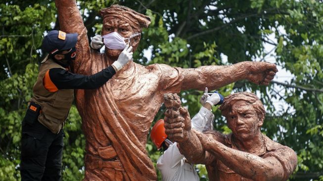 Petugas Badan Penanggulangan Bencana Daerah (BPBD) memasang masker di patung Monumen Djoeang 45 di Pekalongan, Jawa Tengah, Senin (27/4). [ANTARA FOTO/Harviyan Perdana Putra]