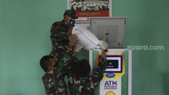 Anggota Kodim 0508/Depok memasukkan beras ke dalam mesin ATM Pertanian Sikomandan di Kodim 0508/Depok, Jawa Barat, Senin (27/4). [Suara.com/Angga Budhiyanto]