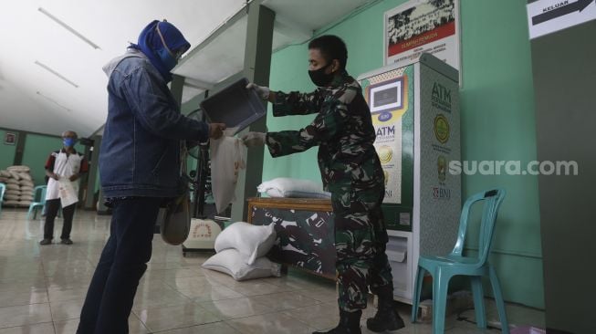 Anggota Kodim 0508/Depok membantu warga mendapatkan beras dengan menggunakan ATM Pertanian Sikomandan di Kodim 0508/Depok, Jawa Barat, Senin (27/4). [Suara.com/Angga Budhiyanto][Suara.com/Angga Budhiyanto]