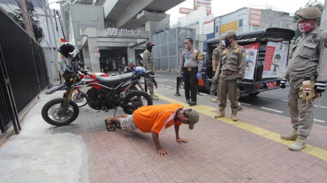 Petugas  memberikan hukuman push up kepada pengendara motor yang tidak memakai masker saat razia Pembatasan Sosial Berskala Besar(PSBB) di Kawasan Jalan Fatmawati, Jakarta, Selasa (28/4).  [ANTARA FOTO/Reno Esnir]