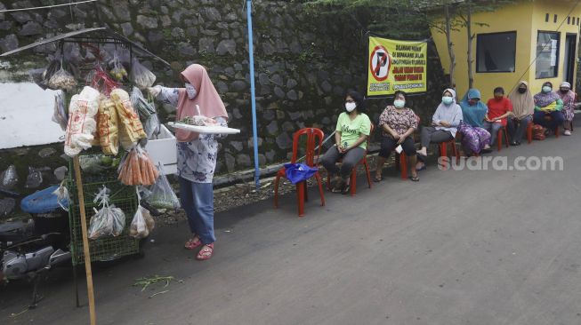 Antrean untuk membeli sayur dengan menjaga jarak di Perumahan Taman Anyelir 3, Cilodong, Depok, Jawa Barat, Selasa (28/4).  [Suara.com/Angga Budhiyanto]