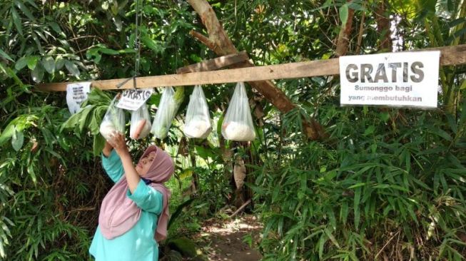 Ardiati, seorang warga Sleman, tengah menggantungkan sayur mayur gratis sebagai bantuan di bulan Ramadan selama pandemi corona di halaman rumahnya di Dusun Rajek Lor, Desa Tirtoadi, Kecamatan Mlati, Rabu (29/4/2020). - (SuaraJogja.id/Muhammad Ilham Baktora)