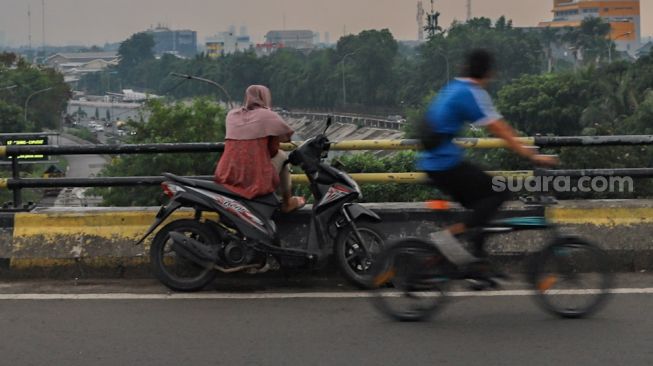 Perempuan ngabuburit di Flyover Pasar Rebo, Jakarta Timur, Kamis (30/4). [Suara.com/Alfian Winanto]