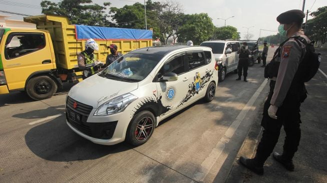 Petugas kepolisian memeriksa dokumen kependudukan dan surat kelengkapan kendaraan bermotor milik warga dari Madura yang masuk ke Surabaya di pintu keluar Jembatan Suramadu, Surabaya, Jawa Timur, Jumat (1/5).   [ANTARA FOTO/Didik Suhartono]