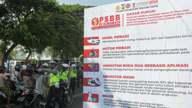 Polisi memeriksa dokumen kependudukan dan surat kelengkapan kendaraan bermotor milik warga dari Madura yang masuk ke Surabaya di pintu keluar Jembatan Suramadu, Surabaya, Jawa Timur, Jumat (1/5).   [ANTARA FOTO/Didik Suhartono]