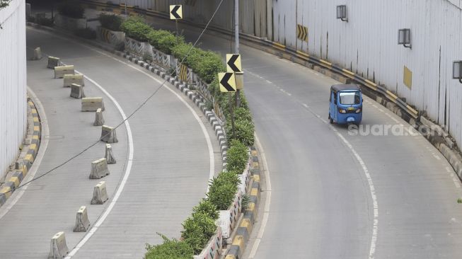 Bajaj melintas di samping underpass Senen yang ditutup di Jakarta, Jumat (1/5).  [Suara.com/Angga Budhiyanto]